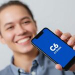 Pessoa sorrindo com celular do C6 Bank