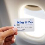 Miles & More Kreditkarte mit Reisepass und Flugzeugfenster