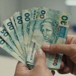 Desmistificando o FGTS: Guia Completo das Regras e Atualizações Essenciais Mão segurando dinheiro do FGTS com fundo desfocado.